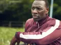 Omar Sy w bordowej bluzie z białymi pasami, gotowy do akcji w kolejnych filmach, serialach i programach.