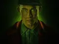 Mężczyzna z zielonymi oczami i czapką na głowie, w tle zielona poświata. Zapowiada mroczne seriale kryminalne Netflix.