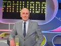 Mężczyzna w garniturze na tle planszy teleturniejowej, wyglądający na siłach i gotowy do gry, by być zdrowym jak Familiada.