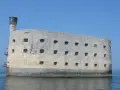 Fort Boyard, imponująca kamienna twierdza na wodzie, z licznymi oknami i wieżą.
