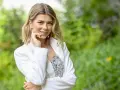 Agnieszka Dziekan, prowadząca Koło Fortuny, w białej marynarce i kwiecistej sukience, z dłonią przy policzku.