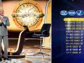 Prowadzący w studio "Milionerów" czeka na pytanie za milion. Na ekranie widoczna jest drabinka nagród.