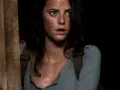 Twarz Kaji Scodelario, aktorki znanej z filmów i seriali, z przerażeniem w oczach, w ciemnym otoczeniu.
