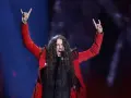 Michał Szpak na Eurowizji w czerwonej marynarce, z uniesionymi rękami i gestem rock'n'rolla.