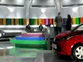 Studio telewizyjne, gdzie nagrywane jest koło fortuny. Widać scenografię z kolorowymi panelami, schodami i czerwonym samochodem.