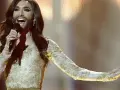 Conchita Wurst, zwyciężczyni Eurowizji, w złotej sukni z cekinami śpiewa na scenie.