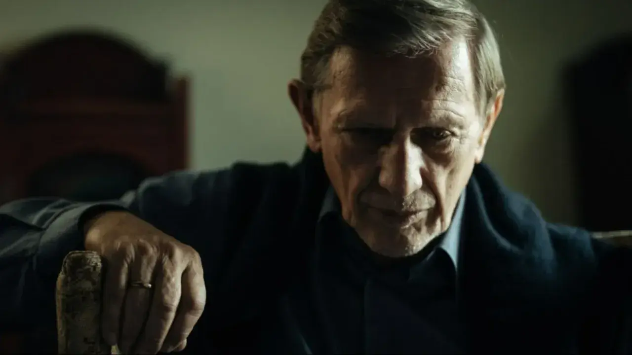 Jan Englert w filmach, zamyślony, z dłonią opartą o laskę.