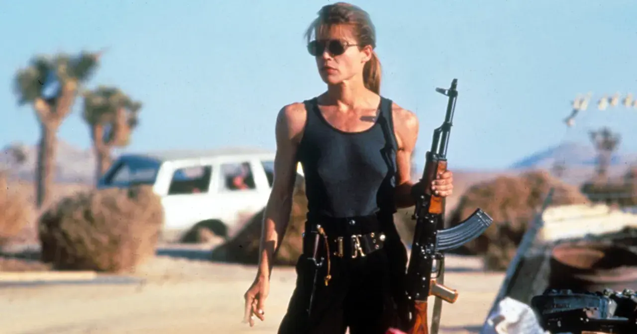 Linda Hamilton w roli Sary Connor, gotowa do walki w pustynnym krajobrazie. Jej ikoniczne role w filmach i serialach na zawsze zapisały się w historii kina.
