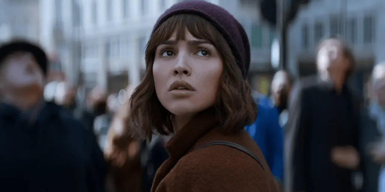 Młoda kobieta w brązowym płaszczu i bordowej czapce patrzy w górę, otoczona tłumem. Czy to zapowiedź netflix nowości dzisiaj?