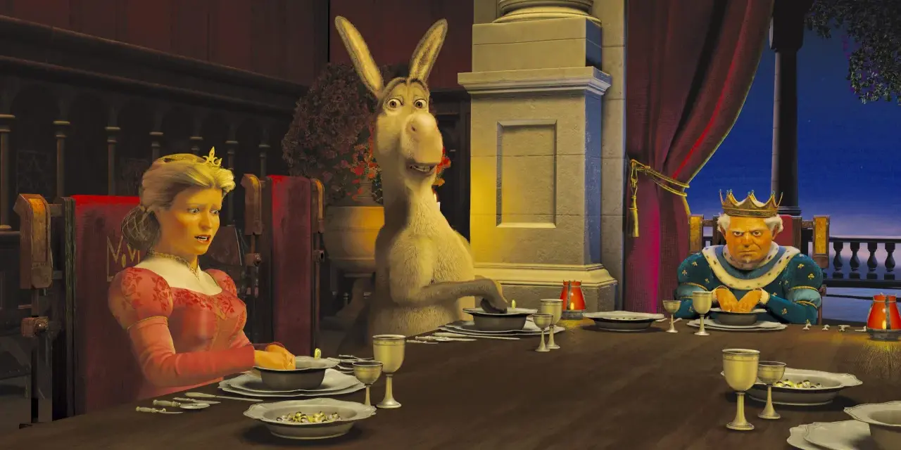 Królowa Fiona, Osioł i Król Harold siedzą przy stole. Scena z filmu DreamWorks.
