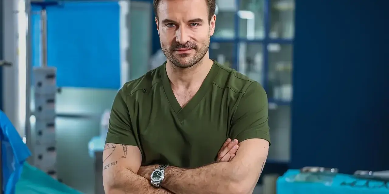 Dr. Witold w zielonym scrubie, z rękami skrzyżowanymi na piersi, w szpitalu św. Anny sezon 2.