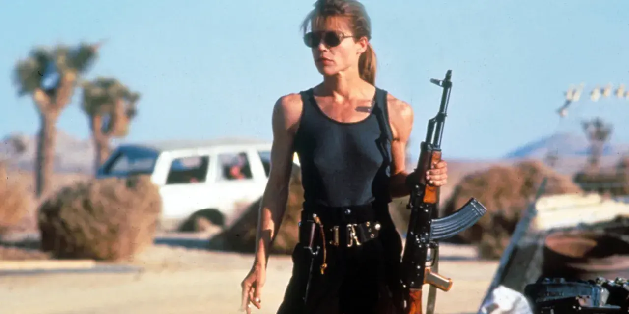 Linda Hamilton w roli Sary Connor, gotowa do walki w pustynnym krajobrazie. Jej ikoniczne role w filmach i serialach na zawsze zapisały się w historii kina.