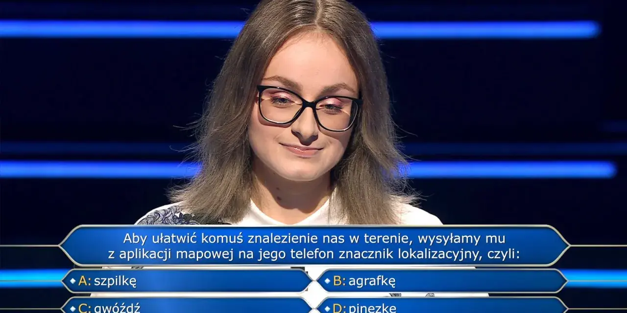 Młoda kobieta w okularach na tle niebieskich pasów, zastanawia się nad pytaniem z teleturnieju: "Aby ułatwić komuś znalezienie nas w terenie, wysyłamy mu z aplikacji mapowej na jego telefon znacznik lokalizacyjny, czyli: B: agrafkę".