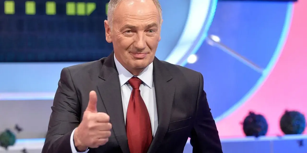 Uśmiechnięty mężczyzna w garniturze pokazuje kciuk w górę. Czy to znak, że wspólnie rozwiążemy Familiadę?