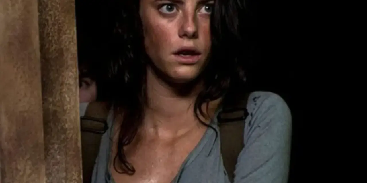 Twarz Kaji Scodelario, aktorki znanej z filmów i seriali, z przerażeniem w oczach, w ciemnym otoczeniu.