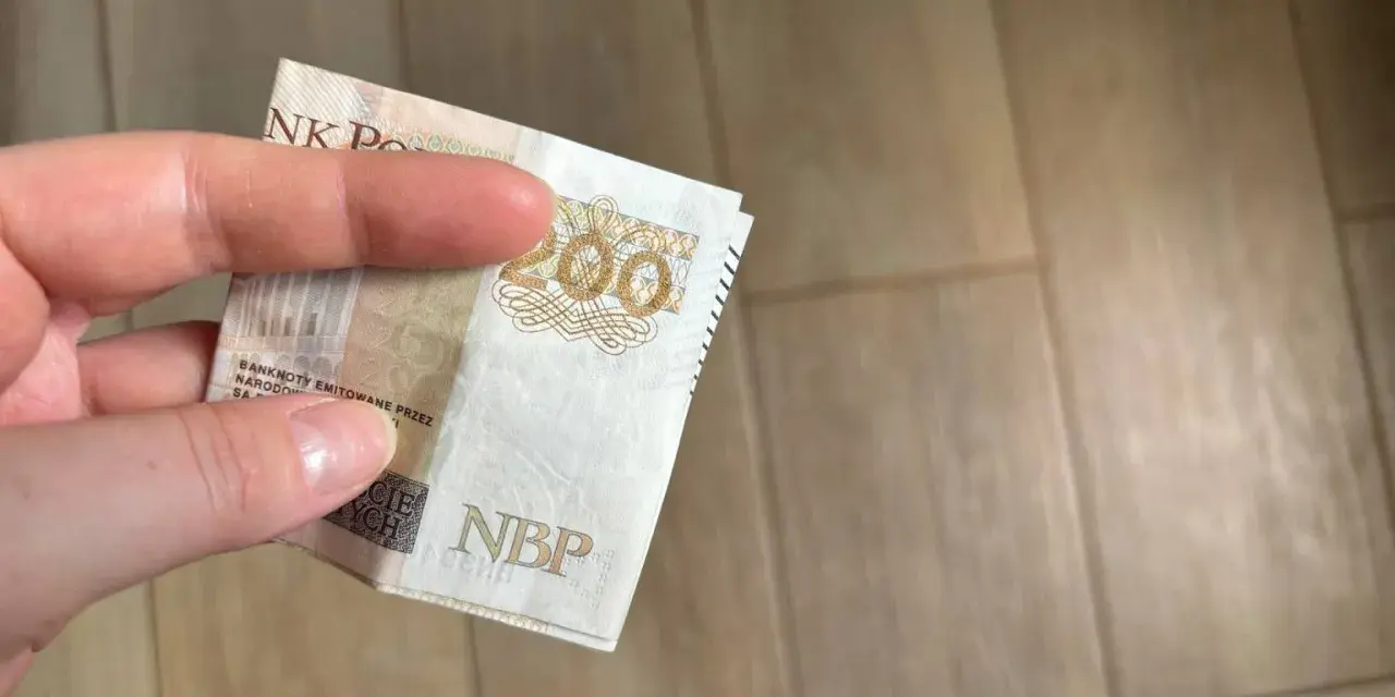 Dłoń trzyma banknot 200 zł. Gdzie można trzymać pieniądze? Familiada podpowie!