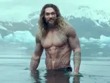 Jason Momoa w wodzie, z tatuażami, jak w filmach i serialach. W tle góry i lód.