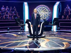 Na scenie "Milionerów" stoi prowadzący. Widownia siedzi w tle. Pytanie brzmi: jakie są koła ratunkowe w Milionerach?