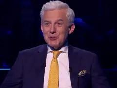 Prowadzący w garniturze z żółtym krawatem, jakby zapowiadał specjalne wydanie "Milionerzy Walentynki gdzie obejrzeć".