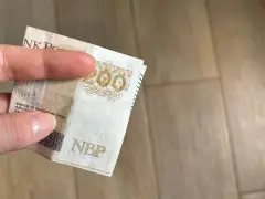 Dłoń trzyma banknot 200 zł. Gdzie można trzymać pieniądze? Familiada podpowie!