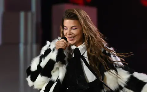 Edyta Górniak w szachownicznym futrze, z różowym makijażem oczu, śpiewa na scenie. Pamiętny występ na Eurowizji.
