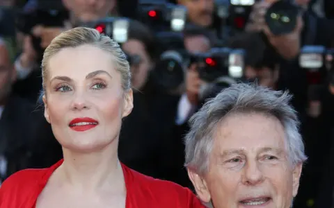 Emmanuelle Seigner, żona Romana Polańskiego, na czerwonym dywanie, otoczona przez fotoreporterów.