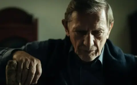Jan Englert w filmach, zamyślony, z dłonią opartą o laskę.