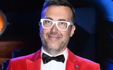 DJ z "Jaka to melodia?" w czerwonej marynarce i białych okularach, gotowy do zabawy.