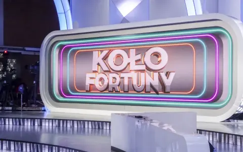 Na scenie studia telewizyjnego widnieje napis "KOŁO FORTUNY" otoczony neonami. To miejsce, gdzie marzenia o wygranej stają się rzeczywistością.