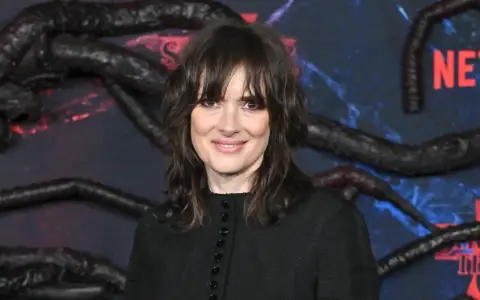 Winona Ryder, gwiazda filmów i seriali, w tym "Stranger Things", na tle dekoracji z mackami i logo Netflix.