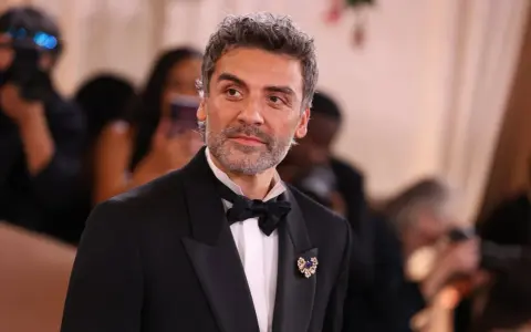 Oscar Isaac w eleganckim smokingu, gotowy na premierę swoich najnowszych filmów, seriali i programów.