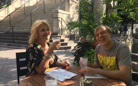 Tom Logan, mąż Majki Jeżowskiej, uśmiecha się do aparatu, siedząc przy stoliku w kawiarni.