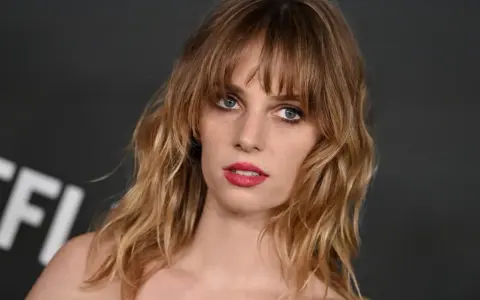 Maya Hawke, znana z filmów, seriali i programów, z burzą blond włosów i wyrazistymi ustami.