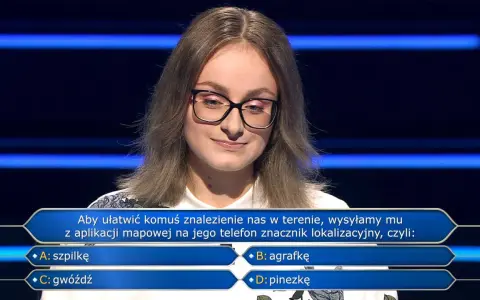 Młoda kobieta w okularach na tle niebieskich pasów, zastanawia się nad pytaniem z teleturnieju: "Aby ułatwić komuś znalezienie nas w terenie, wysyłamy mu z aplikacji mapowej na jego telefon znacznik lokalizacyjny, czyli: B: agrafkę".