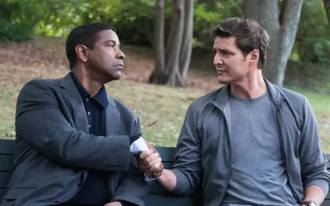 Denzel Washington i Pedro Pascal, obsada "Bez litości 2", siedzą na ławce i ściskają sobie dłonie.