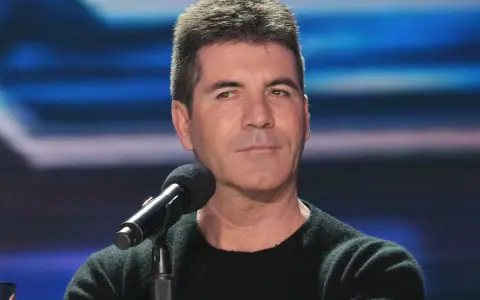 Simon Cowell, znany z surowych ocen, siedzi przy mikrofonie. Plotki o tym, że Simon Cowell nie żyje, są fałszywe.