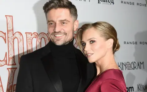 Uśmiechnięta Kaczorowska z partnerem na ściance.