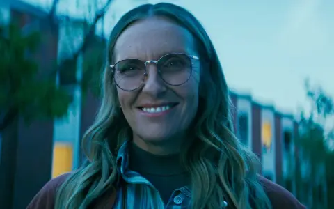 Uśmiechnięta Toni Collette w okularach, znana z wielu filmów i seriali, wygląda na zadowoloną.