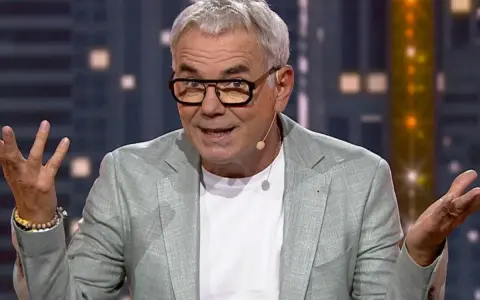 Kto prowadził "Jaka to melodia"? To Hubert Urbański, znany prezenter, w jasnej marynarce i okularach, z gestykulacją.