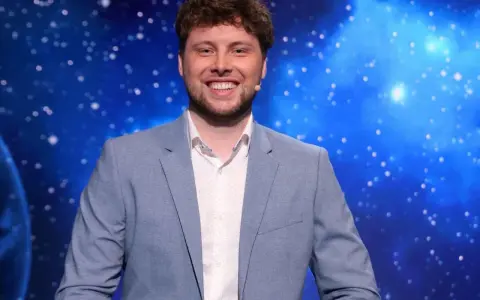 Uśmiechnięty mężczyzna w jasnej marynarce, jeden z dziesięciu jak się zgłosić, na tle kosmicznego nieba.