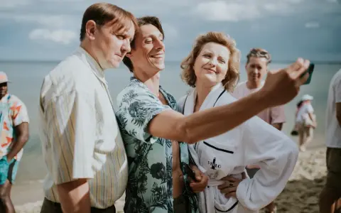 Trzech bohaterów z filmu "Teściowie 2" robi selfie na plaży. Gdzie obejrzeć ten hit?