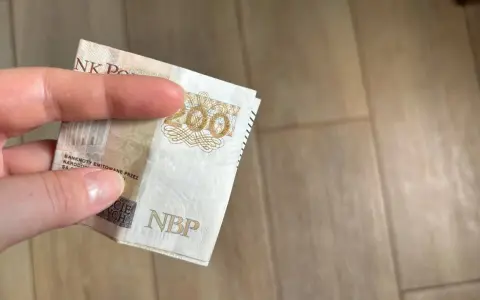 Dłoń trzyma banknot 200 zł. Gdzie można trzymać pieniądze? Familiada podpowie!