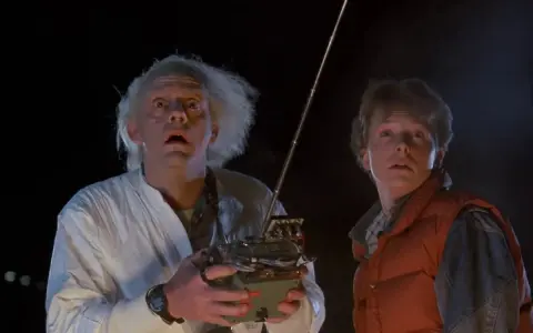 Doc i Marty z "Powrót do przyszłości obsada" z przerażeniem patrzą w niebo, gdy Doc trzyma dziwne urządzenie.