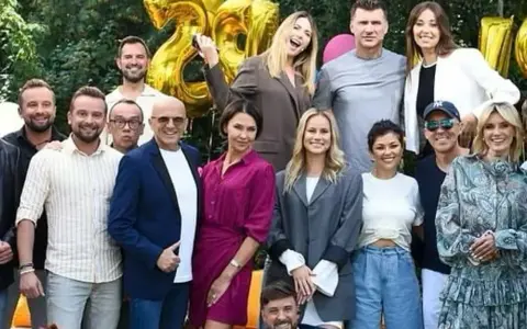 Ekipa TVP2 Pytanie na śniadanie dzisiejszy odcinek świętuje 28 lat! Radosna grupa prezenterów i gości pozuje do wspólnego zdjęcia na tle złotych balonów.