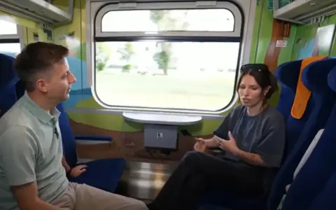 Rozmowa w wagonie z kolorowymi grafikami, być może w ramach specjalnego **metro programu** dla dzieci.