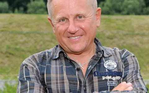 Uśmiechnięty mężczyzna w kratę, z krzyżykiem na szyi. To Bercik, znany z serialu.