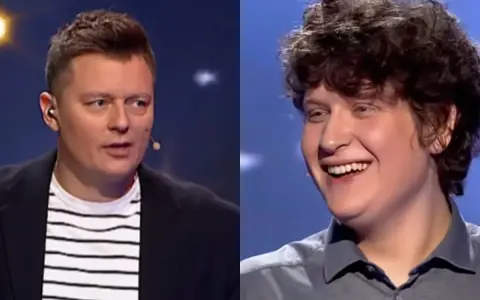 Uśmiechnięty młody uczestnik i prowadzący w okularach na scenie programu "Jaka to melodia finał miesiąca".