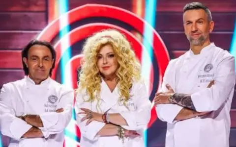 Trzech jurorów MasterChef: Michel Moran, Magda Gessler i Przemysław Klimsa, w białych fartuchach, z rękami skrzyżowanymi na piersi.