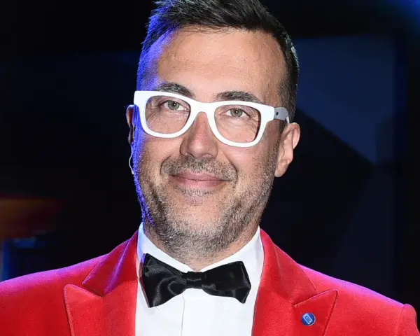 DJ z "Jaka to melodia?" w czerwonej marynarce i białych okularach, gotowy do zabawy.