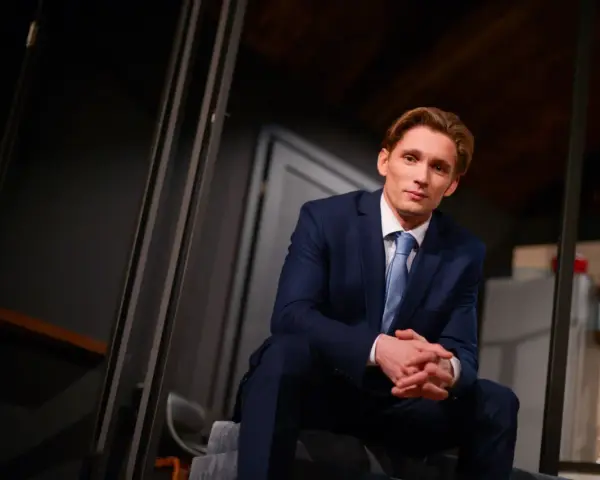 Filip Gurłacz w garniturze, siedzi na schodach, zastanawiając się, jaka to melodia.